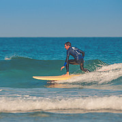 Position stable sur une petite vague verte Take-off réussi – tu tiens fermement debout et surfes ta première vague verte.