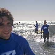 Élèves en cours de surf à Fuerteventura Débutant en surf pagayant sur sa planche dans les eaux peu profondes du cours.
