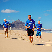 Échauffement pour ton cours de surf sur la plage de Fuerteventura Tu fais un petit jogging le long de la plage infinie – échauffement parfait pour commencer ton cours de surf à Fuerteventura.