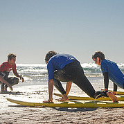 Entraînement au take-off sur la plage Moniteur de surf montrant les mouvements de take-off à sec pendant un cours pour débutants.